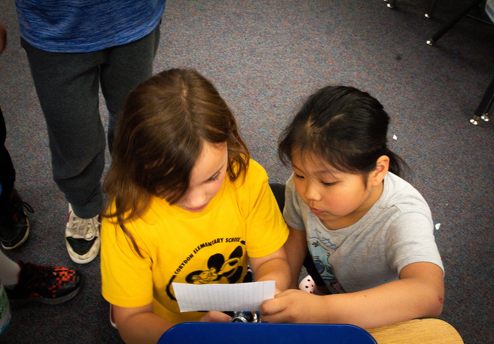 Two girls reading a code to unlock a breakout box