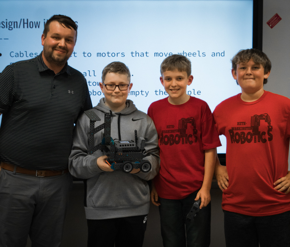 Mr. Yeager and three male students holding a robot