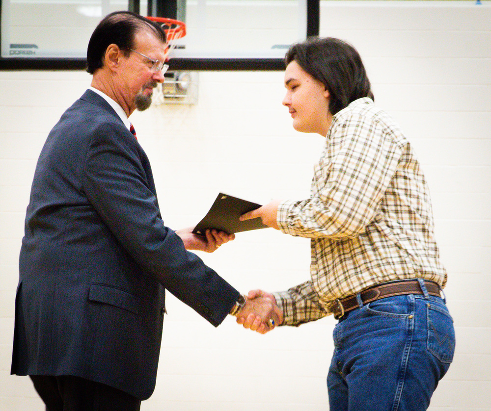 Dr. Eastridge, male in a suit, handing a male student an award while shaking hands