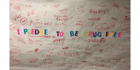 banner titled "I Pledge to be Drug-Free" with student signatures