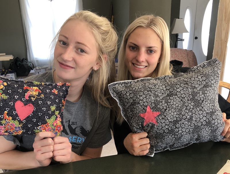Two girls holding up pillows and smiling