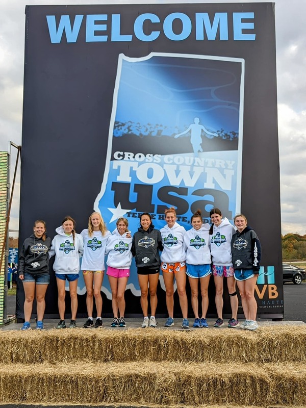 Group of Corydon Cross Country runners standing in front of a sign